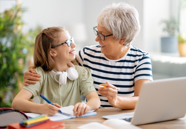 Zurück zur Schule. Glückliches Kind und Erwachsener sitzen am Schreibtisch. Mädchen, das Hausaufgaben oder Online-Bildung macht.