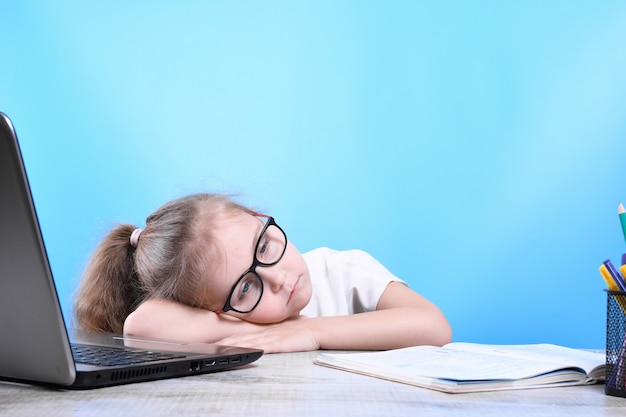 Zurück zur Schule. Glückliches süßes fleißiges Kind sitzt drinnen an einem Schreibtisch. Kind lernt im Unterricht zu Hause mit Laptop, Computer