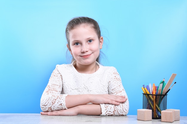 Zurück zur Schule. Glückliches süßes fleißiges Kind sitzt drinnen an einem Schreibtisch. Kind lernt im Unterricht.