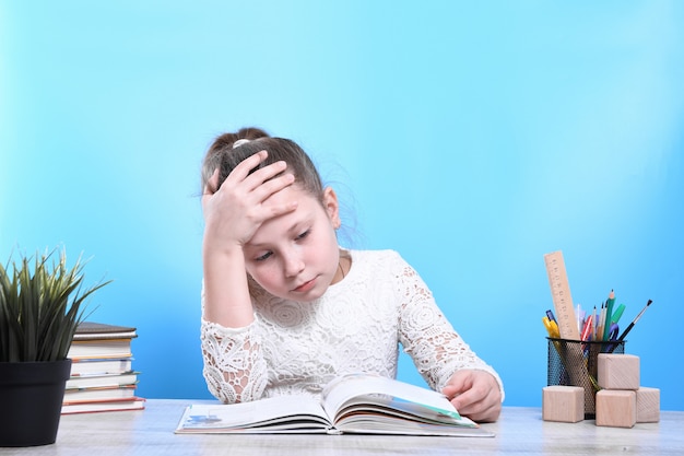 Zurück zur Schule. Glückliches süßes fleißiges Kind sitzt drinnen an einem Schreibtisch. Kind lernt im Unterricht.