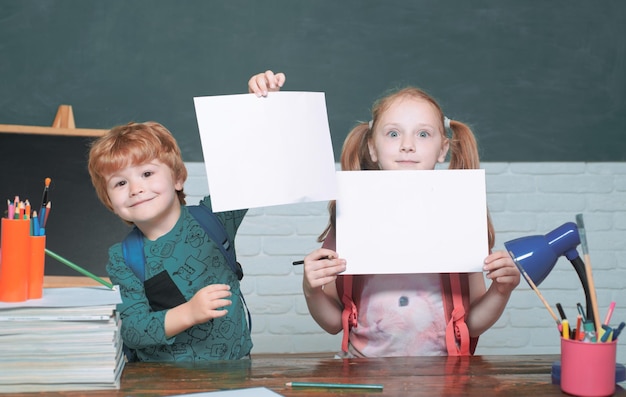 Zurück zur Schule lustige kleine Kinder, die nach oben auf den Kopierraum des Schulkonzepts der Tafel zeigen