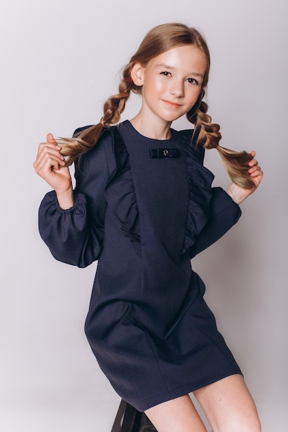 Zurück zur Schule. Nettes entzückendes kaukasisches blondes Mädchen in der Schuluniform auf weißem Hintergrund