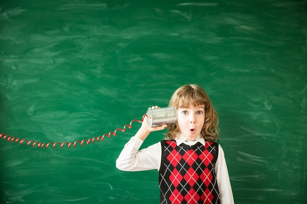 Zurück zur Schule Schulkind in der Klasse Glückliches Kind gegen grüne Tafel Bildung und Kreativität