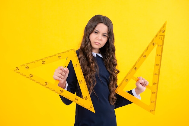 Zurück zur Schule Schulmädchen halten das Lineal, das auf gelbem Hintergrund isoliert misst Wütendes Teenager-Mädchen verärgert und unglücklich negative Emotionen