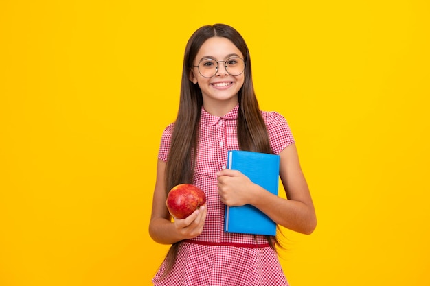 Zurück zur Schule Teenager-Schülerin mit lernbereitem Buch Schulmädchenkinder auf isoliertem gelbem Studiohintergrund