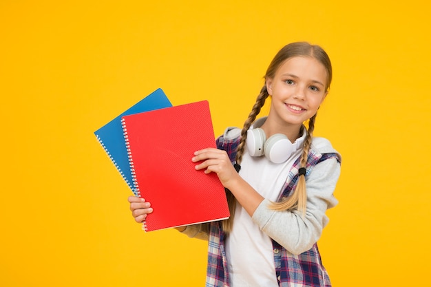 Zurück zur Schule. Verwenden Sie ein Notizbuch oder ein Buch. Studienunterricht für die Prüfung. Inspiration im Buch finden. Freude am Studium. Vertrauen in ihr Wissen. kleines Kind im Headset mit Notizblock. Kind bereit zu lernen.