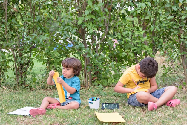 Zurück zur Schule Zwei glückliche und fröhliche Kinder, ein Schuljunge mit Notizbüchern und Farben in den Händen im Park