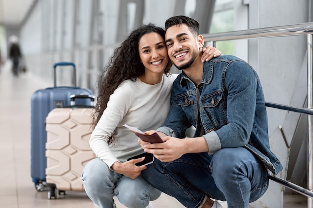 Zusammen reisen Porträt von glücklichen Ehepartnern aus dem Nahen Osten, die am Flughafen posieren