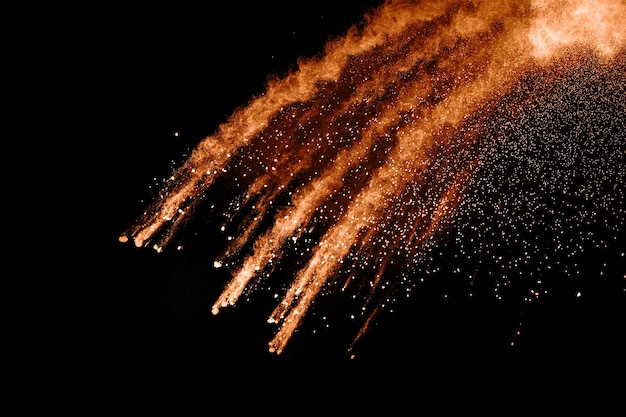 Zusammenfassung orange Pulver Explosion auf schwarzem Hintergrund.