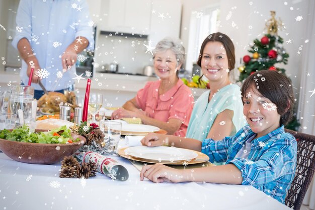 Zusammengesetztes Bild der Familie beim Weihnachtsessen gegen Schneefall