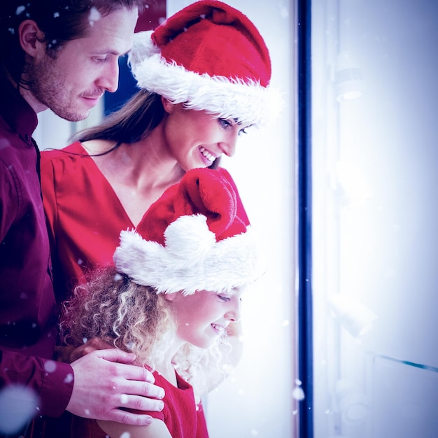 Zusammengesetztes Bild der Seitenansicht der Familie in Weihnachtskleidung mit Blick auf die Anzeige