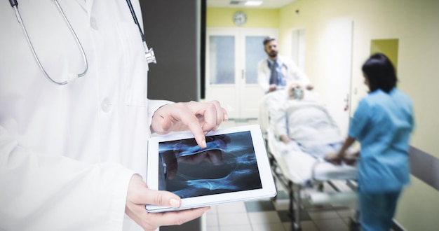 Zusammengesetztes Bild des Arztes, der Röntgenstrahlen auf Tablet betrachtet