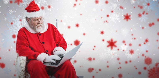 Zusammengesetztes Bild des ernsten Weihnachtsmanns unter Verwendung des Laptops
