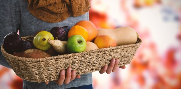 Zusammengesetztes Bild des Mittelteils der Frau, die Obst und Gemüse im Korb hält