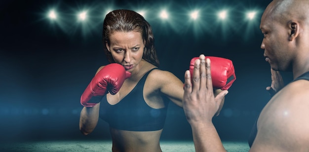 Zusammengesetztes Bild des weiblichen Boxers, der mit Trainer übt