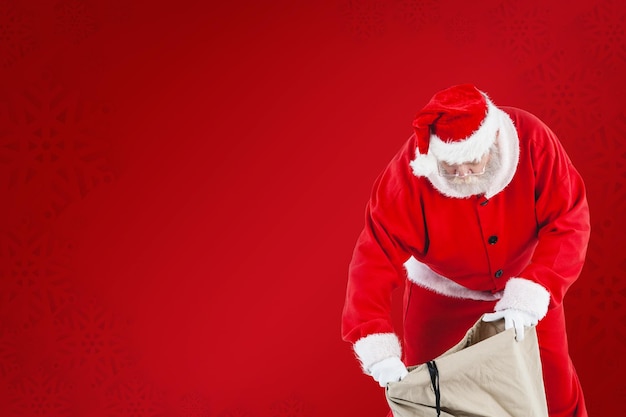 Zusammengesetztes Bild des Weihnachtsmanns, der Geschenkboxen im Sack füllt
