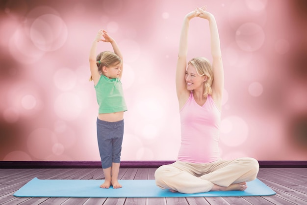Foto zusammengesetztes bild einer schwangeren lächelnden mutter und tochter, die zusammen yoga machen