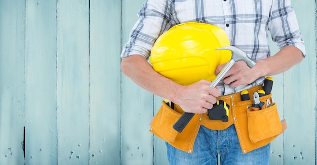 Zusammengesetztes Bild von Carpenter Torso mit Hammer gegen blaue Holzplatte