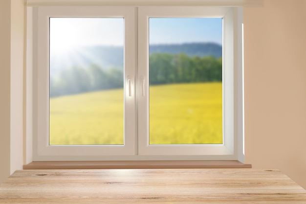 Zusammengesetztes Bildmodell eines leeren Tisches auf dem Hintergrund einer wunderschönen sonnigen Berglandschaft in einem Zimmerfenster