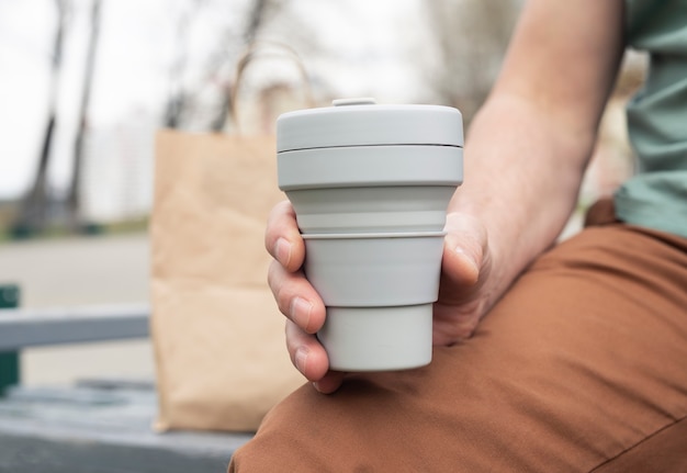 Zusammenklappbarer Silikon-Eco-Becher für Kaffee zum Mitnehmen. Männliche Hand mit nachhaltiger Tasse.