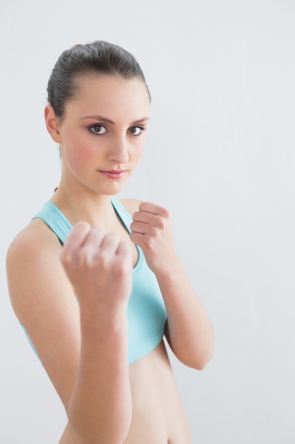 Zusammenpressende Fäuste der sportlichen Sitzfrau gegen Wand