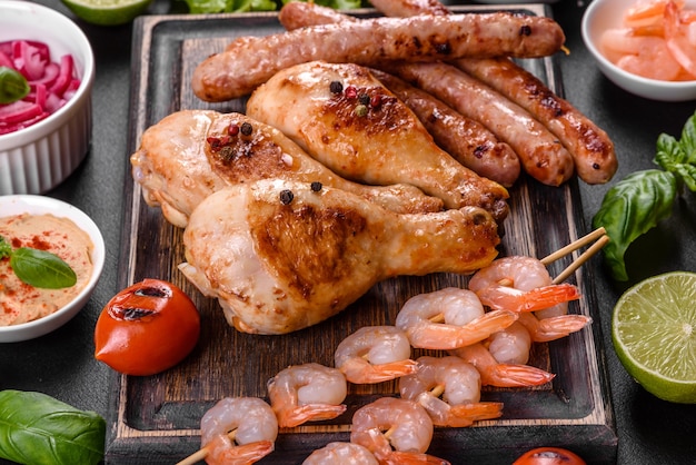 Zusammensetzung aus Würstchen, Hühnchen, Schweinefleisch und Garnelen auf dem Grill zubereitet sowie Gemüse auf dem Grill mit Gewürzen und Kräutern zubereitet. Kochen auf Feuer