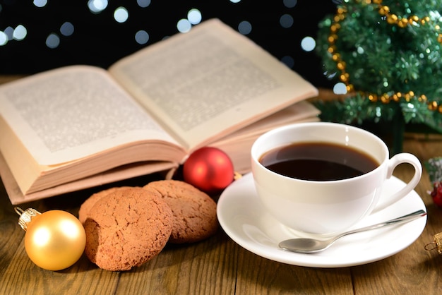 Zusammensetzung des Buches mit Tasse Kaffee und Weihnachtsschmuck auf dem Tisch auf dunklem Hintergrund