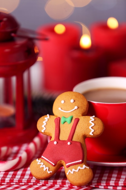 Zusammensetzung des leckeren Lebkuchenplätzchens und der Tasse Kaffee auf Küchentisch, Nahaufnahme