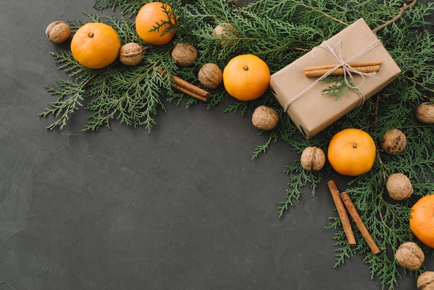 Zusammensetzung des Weihnachtsneuen Jahres mit Tangerine-Kasten-Kiefernkegel Grüns in der schwarzen Hintergrund-Feiertags-Dekoration getont