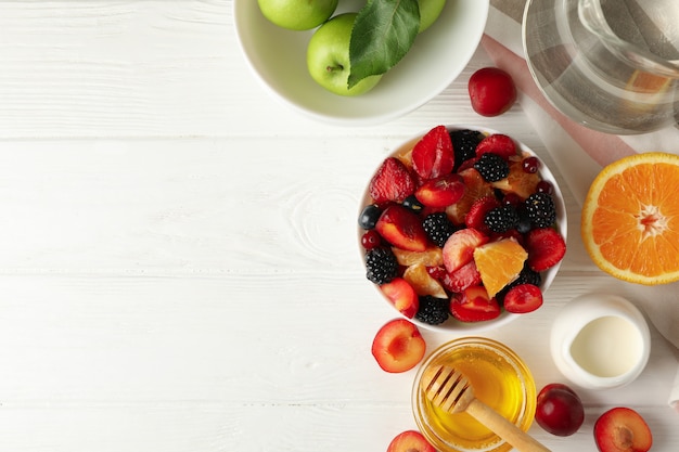 Zusammensetzung mit frischem Obstsalat auf weißem Holztisch