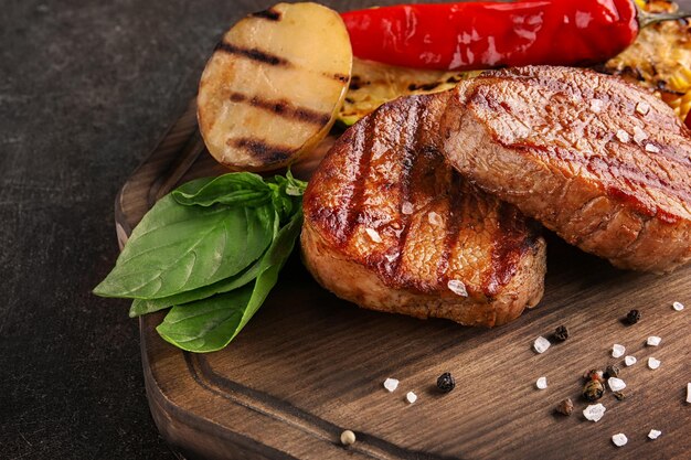 Zusammensetzung mit leckeren gegrillten Steaks auf dem Tisch in der Nähe