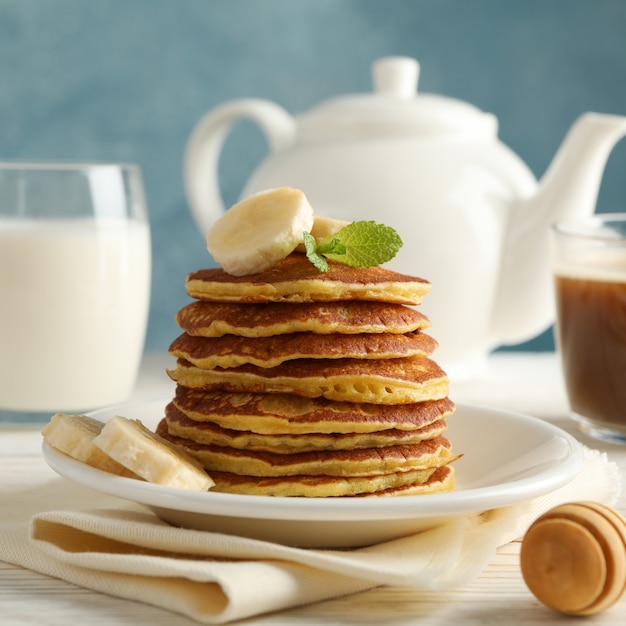 Zusammensetzung mit Pfannkuchen, Milch und Kakaogetränk auf Holztisch. Süßes Frühstück