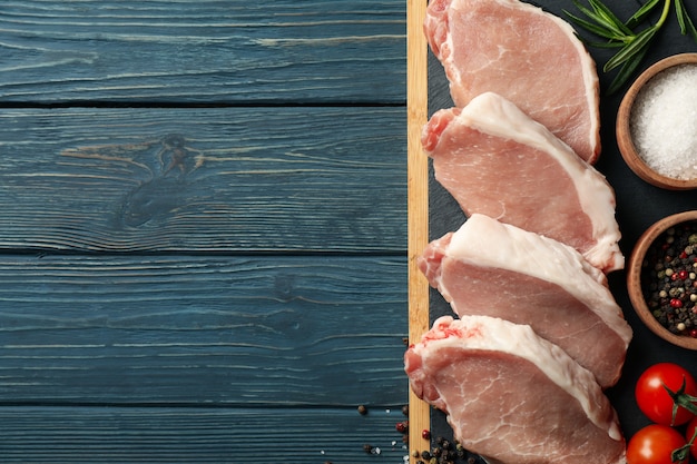 Zusammensetzung mit rohem Fleisch für Steak und Zutaten auf Holztisch