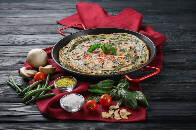 Zusammensetzung mit Spinat-Frittata in der Bratpfanne auf dem Tisch