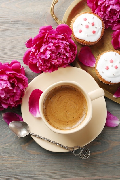 Foto zusammensetzung mit tasse kaffeemuffins und pfingstrosenblumen auf hölzernem hintergrund beschneidungspfad eingeschlossen