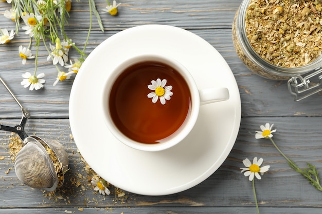 Zusammensetzung mit Tasse Kamillentee auf weißem hölzernem Hintergrund