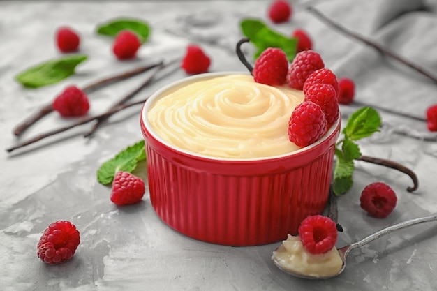 Zusammensetzung mit Vanillepudding, frischer Minze und Himbeeren auf grauem Tisch