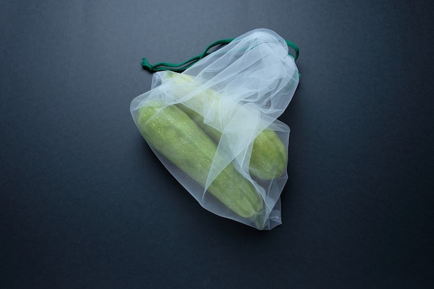 Zusammensetzung mit Zucchini in einer Schnurtasche auf einem schwarzen Hintergrund. Kein Verlust.