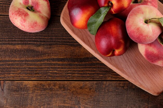 Zusammensetzung vieler Pfirsichsorten auf einem braunen Holztisch. Früchte.