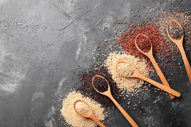 Zusammensetzung von Amaranth, Quinoa, Chia in Holzlöffeln auf schwarzem Hintergrund