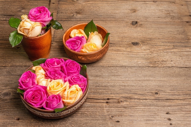 Zusammensetzung von frischen mehrfarbigen Rosen im Küchengerät. Das festliche Konzept für Hochzeiten, Geburtstage, 8. März, Mutter- oder Valentinstag. Grußkarte, flach, Vintage-Holztisch