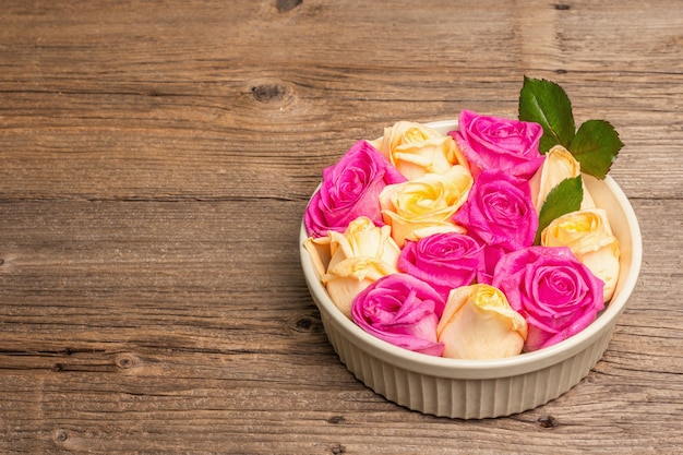 Zusammensetzung von frischen mehrfarbigen Rosen in Keramikschale. Das festliche Konzept für Hochzeiten, Geburtstage, 8. März, Mutter- oder Valentinstag. Grußkarte, flach, Vintage-Holztisch