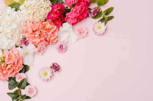 Zusammensetzung von gemischten Blumen auf rosa Hintergrund. Ansicht von oben, Kopienraum.