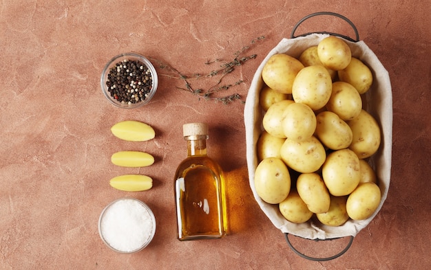 Zusammensetzung von jungen Kartoffeln, Gewürzen, Butter, Küchenutensilien. Kochkonzept. auf farbigem Hintergrund mit Platz für Text