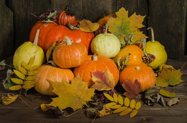 Zusammensetzung von Kürbissen und Herbstlaub auf einer alten Holzoberfläche