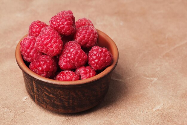 Zusammensetzung von reifen Himbeeren in einer Schüssel auf einem strukturierten Hintergrund