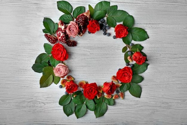 Foto zusammensetzung von rosen, feigen, heidelbeeren und granatapfelstücken auf holzhintergrund