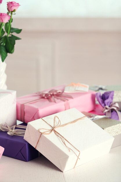 Zusammensetzung von süßen Geschenkboxen und Rosen auf weißem Tisch
