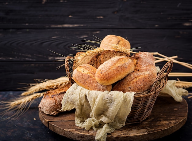 Zusammenstellung des gebackenen Brotes und des Brötchens auf einem hölzernen Hintergrund