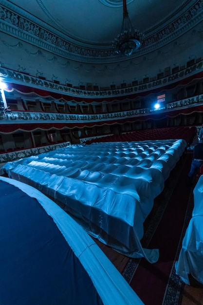 Zuschauerraum eines Theaters von der Bühne aus Stühle im Zuschauerraum mit weißem Tuch zum Schutz vor Staub und Schmutz